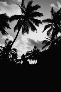 Low angle view of trees against cloudy sky