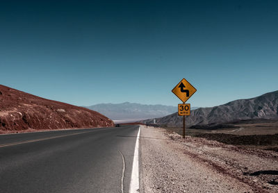 Road signs on landscape against clear sky