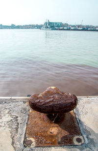 Close-up of rusty metal on shore against sky