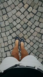 Low section of woman standing on cobblestone