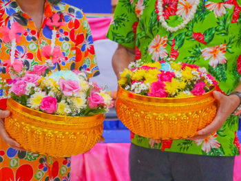 Low section of woman standing by pink flowers in basket