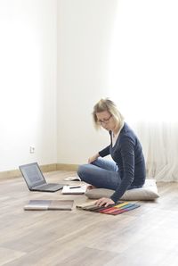 Woman using phone while sitting on hardwood floor