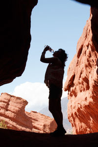Silhouette young woman drinking water while standing in cave
