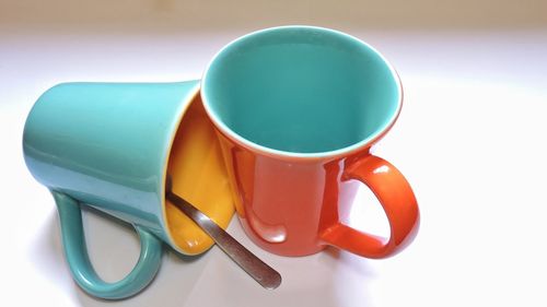 Close-up of orange coffee cups on white background