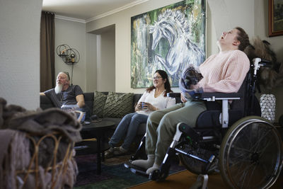 Parents with disabled daughter in wheelchair relaxing in living room