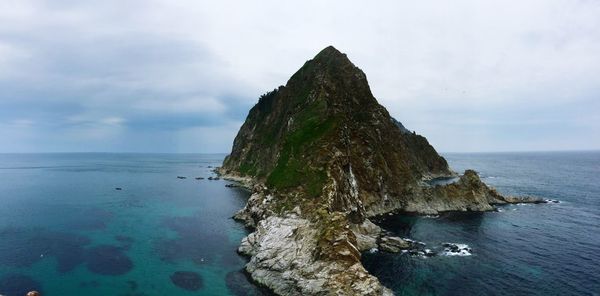 Rock formation in sea against sky