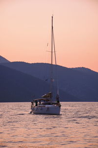 Sailboat sailing on sea against sky during sunset