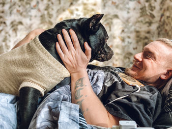 Low section of man with dog relaxing outdoors