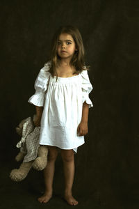 Portrait of smiling girl standing against black background