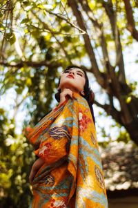 Low angle view of woman standing against tree