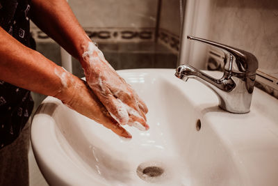 Midsection of man washing hands in sink