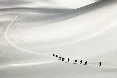 People climbing on snow covered mountain at swiss alps