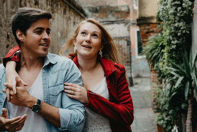 Young couple holding hands in alley while looking away