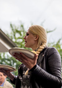 Low angle view of woman holding plate while standing in yard