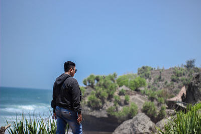 Rear view of man standing against sea