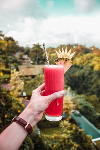 A hand with glass of watermelon juice on the jungle forest background. bali, indonesia