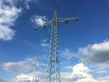 Low angle view of electricity pylon against blue sky