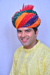 Portrait of smiling man wearing colorful turban against wall
