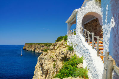 Building by sea against clear blue sky