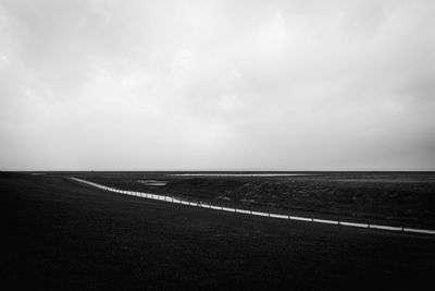 Scenic view of road by sea against sky