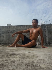 Shirtless boy on beach against sky