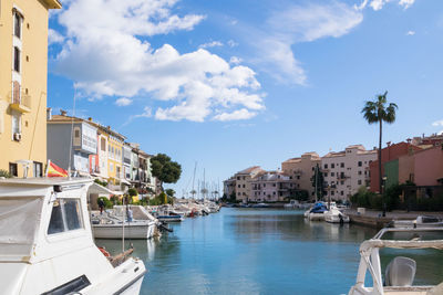 Sailboats moored on sea by buildings in city against sky