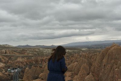 Rear view of woman standing on landscape against sky