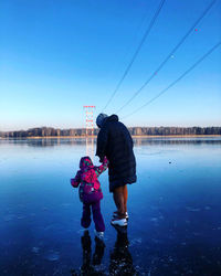 Rear view of people on lake against blue sky