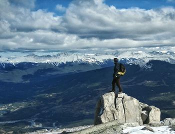 Rear view of man standing on rock against sky