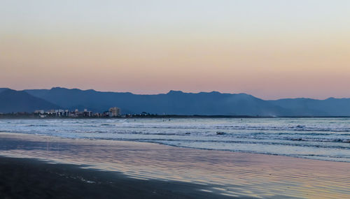 Scenic view of beach against clear sky during sunset