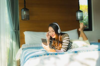 Young woman using mobile phone on bed