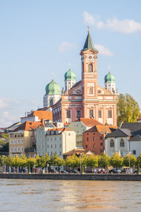 Buildings by river against sky