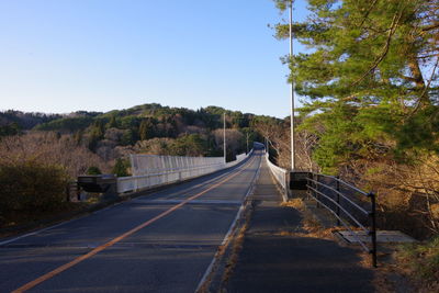 Road leading towards mountain against clear sky