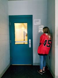 Rear view of woman standing against door