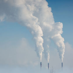 Low angle view of smoke emitting from chimney against sky