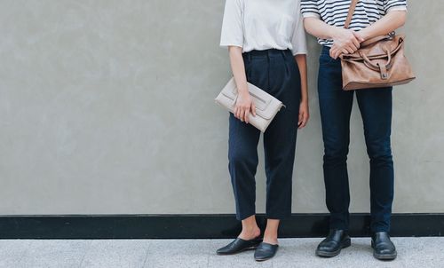 Low section of couple standing against wall