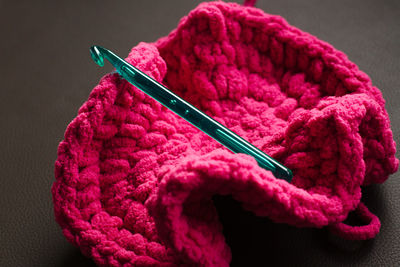 High angle view of green crochet on pink hat over table