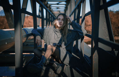 Portrait of young woman sitting on railing