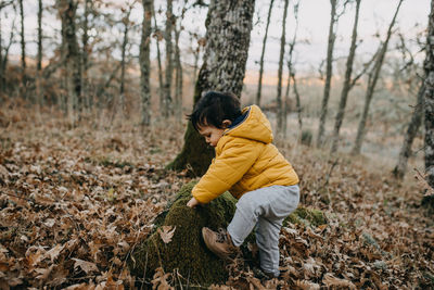 Side view of boy standing in forest