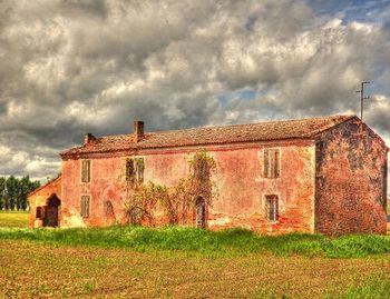 Houses on field against cloudy sky