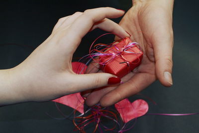 Cropped hands of people holding gift over table