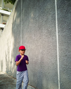 Boy running on footpath by concrete wall