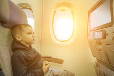 Little boy traveling by airplane. child sitting by aircraft window and looking on monitor. traveling