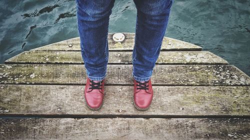 Low section of man standing on pier in lake