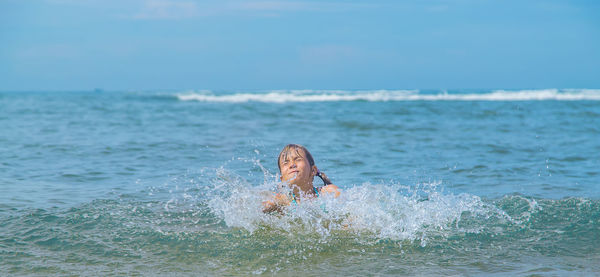 Man swimming in sea against sky