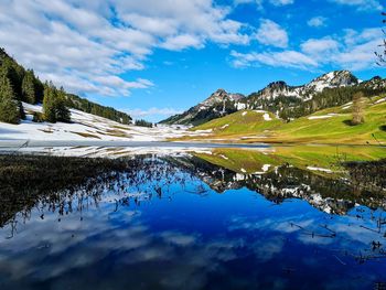 Scenic view of lake and mountains against blue sky