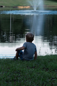 Rear view of man sitting by lake