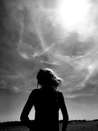 Rear view of silhouette woman standing against sky