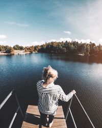 Rear view full length of woman standing by lake on pier