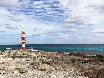 Lighthouse by sea against sky